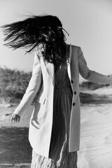monochrome photo of a woman in a jacket against a clear sky on the coast
