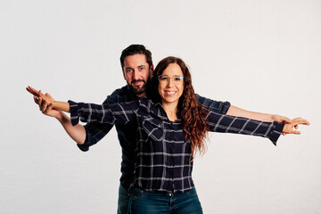An adult couple stretching arms and smiling while looking at camera against a white background - 565320591