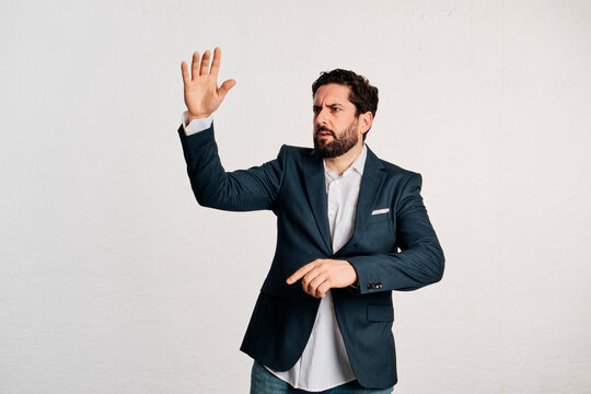 An adult businessman looking away standing with his hand raised and with an expression of seriousness in a studio shot