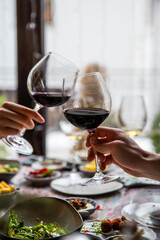 Obraz premium Close up of hands young couple clinking with glasses of red wine at restaurant