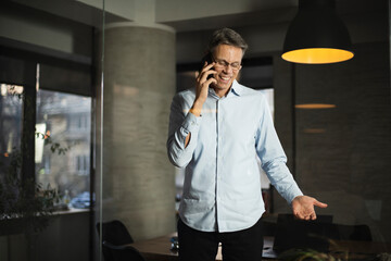 Businessman in office. Handsome man talking on phone at work