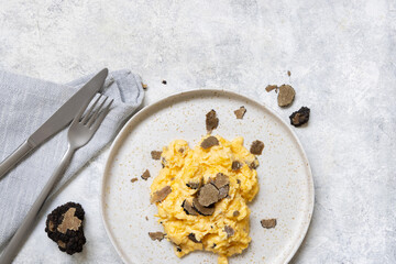 Fototapeta na wymiar Scrambled eggs with fresh black truffles from Italy served in a plate top view, gourmet breakfast