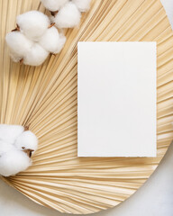 Blank card on dried palm leaf with cotton flowers top view, wedding mockup