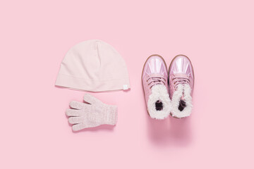 Fashionable children's boots, a hat and gloves for a girl on a pink background. Top view, flat lay.