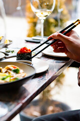 Gunkan maki sushi with salmon and spicy sauce in man hand on restaurant
