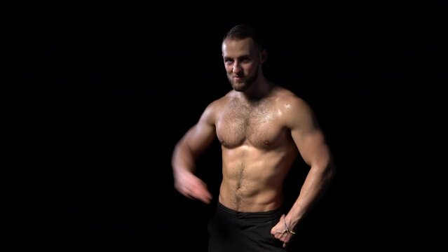 Shirtless muscular man dancing happy on black background, locked down real time video