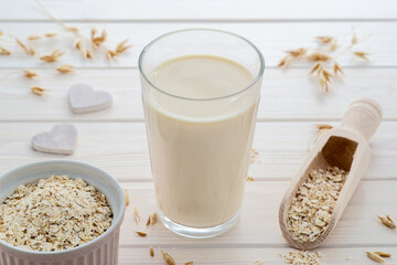 vegan and plant based oat milk in a glass, cereal grain around, plant milk