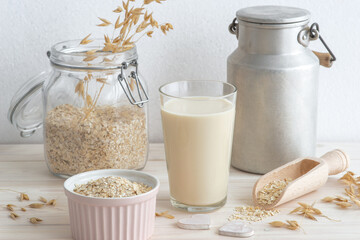 plant based oat milk in a glass, cereal grain and bottle around