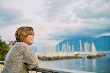 Outdoor portrait of happy preteen boy admiring beautiful water landscape,  image taken in Lausanne, Switzerland