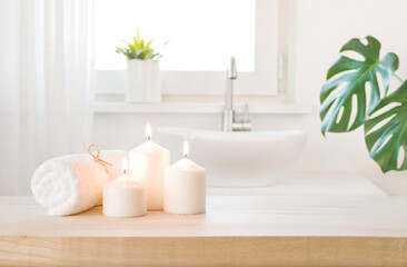 Fototapeta na wymiar Spa towel and burning candles on table with bathroom background