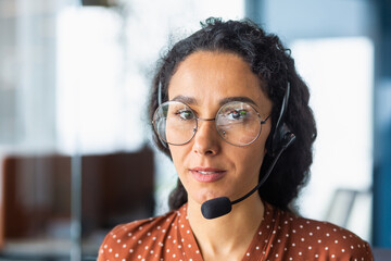 Close-up photo. Portrait of a young beautiful Latin American woman in a headset. Call center,...