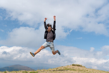photo of jumping man in a mountain. jumping man outdoor. jumping man in full length.