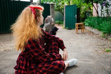 a girl sits with a black cocker spaniel on the road 