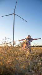 Fototapeta na wymiar a girl with a bouquet of flowers walks on a field with windmills 