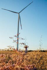 Fototapeta na wymiar a girl with a bouquet of flowers walks on a field with windmills