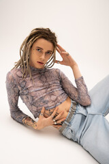 Stylish nonbinary person posing and looking at camera on white background.