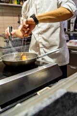 man chef cooking fried salmon fish in frying pan on kitchen