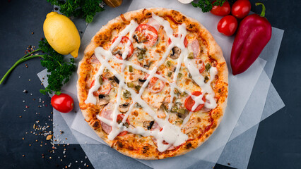 Italian cuisine pizza with mushrooms, tomatoes, ham, pickled cucumber, cheese and sauce.