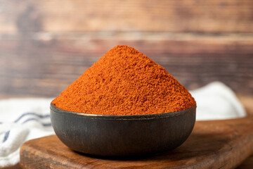 Red chili powder spice. Ground sweet paprika spice in bowl on wood background. Dry spice concept....