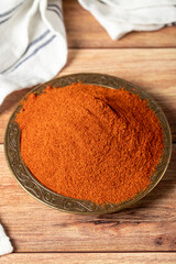 Red chili powder spice. Ground sweet paprika spice in bowl on wood background. Dry spice concept. close up