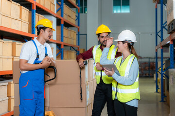 Asian employees work together to check goods in a large warehouse.