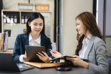 Lawyer businessman and two business partners working together in office. Business women sitting at desk and making notes.