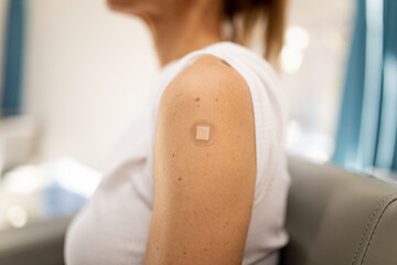 Close up shot of a woman's arm with a circular band aid from a shot