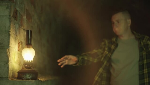 Kerosene lamp in the dungeon. A man takes a gas vodka in his hands. Mysticism, research, expedition, cave. The boy descends into the cave. High quality 4k footage