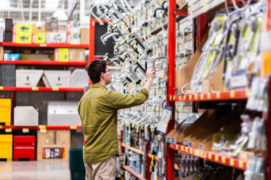 Young adult browsing tap fittings and shower heads for diy bathroom in hardware store