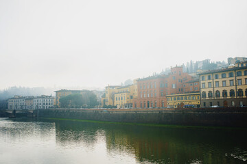 View of the Arno River in Italy and the historic bridge with the reflection of beautiful colorful houses in the water