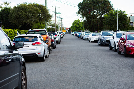 Parked cars lining both sides of narrow road in town during event
