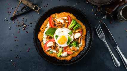 Large potato pancake with chanterelle mushrooms, tomatoes, broccoli, egg, onion, herbs and sour cream in a frying pan.