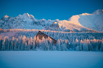 Frosty winter morning at Strbske Pleso under the High Tatras, with the first rays of sunlight illuminating the snow-covered landscape