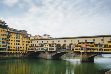 View of the Arno River in Italy and the historic Ponto Vecchio bridge with reflection in the water