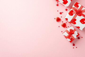 Valentine's Day concept. Top view photo of gift boxes with ribbon bows heart shaped candies and sprinkles on isolated light pink background with copyspace