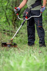 Gardening concept. Man cutting the lawn with grass trimmer.