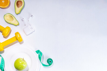 Spring slim and fitness, active living concept. Small yellow dumbbells, bottle of water, sports shoes, scales, salad, fresh vegetables and fruits on a light white background, top view copy space