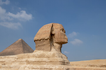 Fototapeta na wymiar Beautiful profile of the Great Sphinx including pyramids in the background on a clear sunny, blue sky day in Giza, Cairo, Egypt