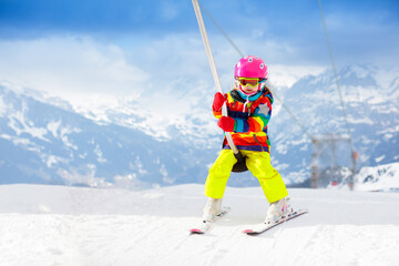 Child on ski lift in snow sport school in winter mountains