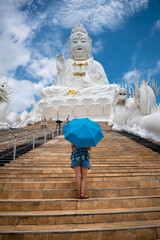 Mujer con paraguas entrando a templo Wat Huay Pla Kang, mirando estatua gigante de Lady Buda, en...