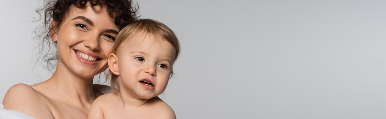 happy mother and toddler baby girl covered in duvet isolated on grey, banner.
