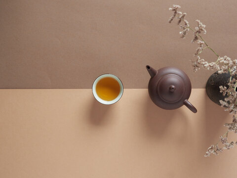 Top View Of Cup With Hot Tea Placed Near Teapot And Vase With Dried Flowers