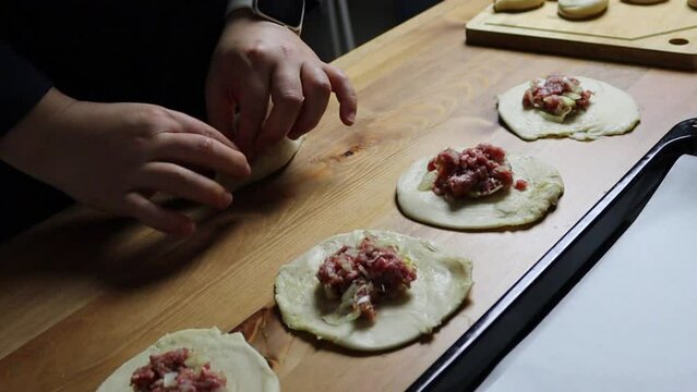 female hands put minced meat filling in puff pastry, homemade food, samsa making, traditional uzbek food