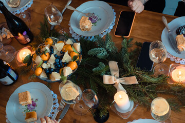 Christmas dinner with tangerines, candles and spruce branches for decoration