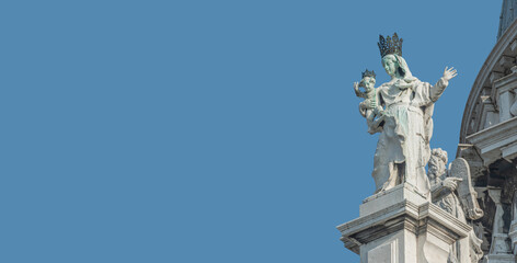Fototapeta na wymiar Banner with ancient sculpture of beautiful Venetian Noble Renaissance Era woman with child at Basilica di Santa Maria della Salute in Venice, Italy, at blue sky solid background with copy space.