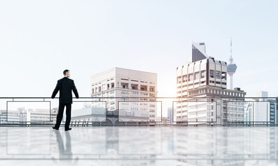 Sunrise above skyscrapers and businessman facing new day