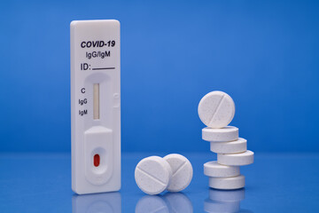 Coronovirus blood test with white tablets to treat illness, blood sample to detect disease on blue background macro shot