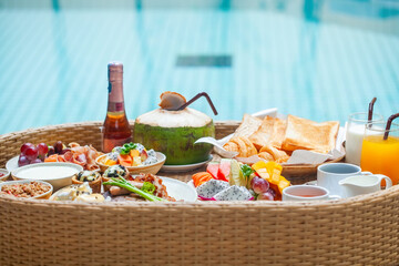 Floating breakfast tray in swimming pool with variety of tropical fruits