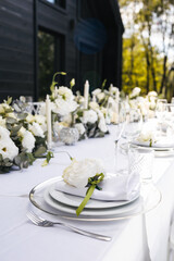 Wedding decorations. Served wedding table with decorative fresh white flowers and candles. Celebration details. flower composition roses plates and candles in candlesticks