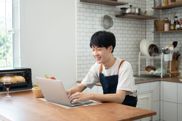Fototapeta premium Young man learning to cook while watching tutorials in internet..